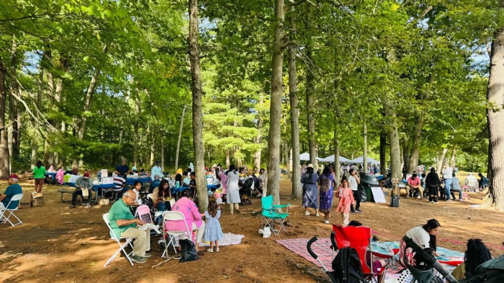 Families spread out on blankets and folding chairs among the pine trees at Houghton's Pond.