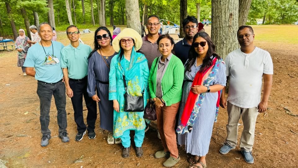 A group of attendees posing together in front of the tree line.