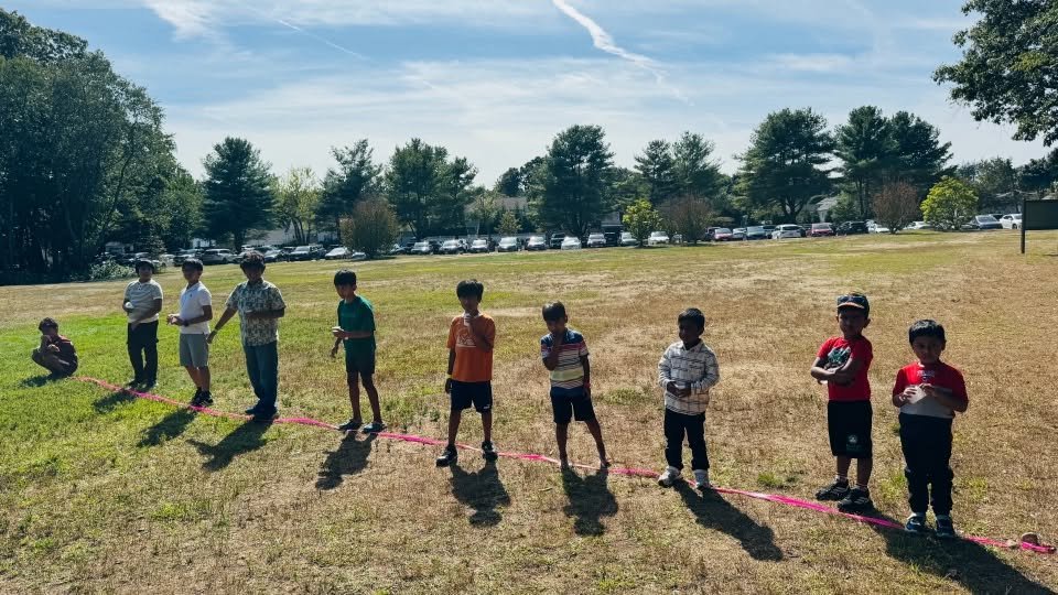 Children lined up at the start of a race on the open field.